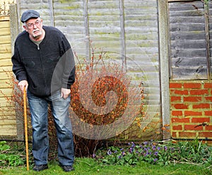 Senior man standing using a stick for support..