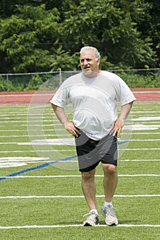 Senior man stretching exercising sports field