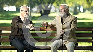 Senior man suffering age-related Alzheimer disease, old friends talking in park