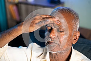 Senior man suffering from headache - concept of stress, family problems and illness during coronavirus covid-19 lockdown