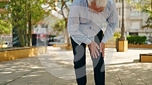 Senior man suffering for knee pain walking at park