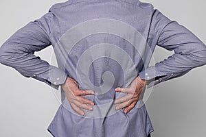 Senior man suffering from pain in back on light grey background, closeup. Arthritis symptoms