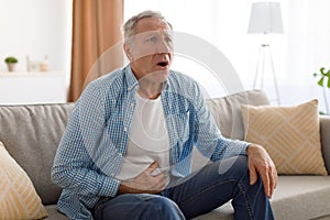 Senior man suffering from stomachache, touching tummy