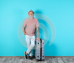 Senior man with suitcase near color wall