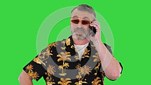 Senior man in sunglasses talking by smartphone on a Green Screen, Chroma Key.