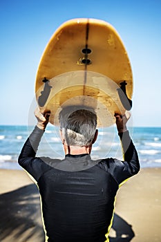 A senior man with a surfboard