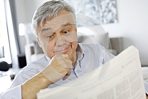 Senior man with surprised look reading newspaper