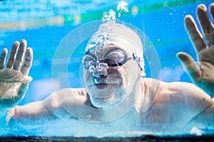 Senior man swimming in an indoor swimming pool.