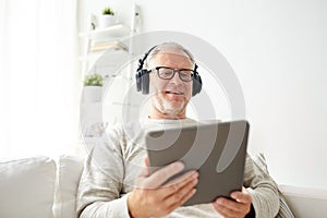 Senior man with tablet pc and headphones at home