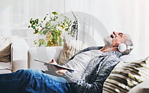 Senior man with tablet relaxing at home.