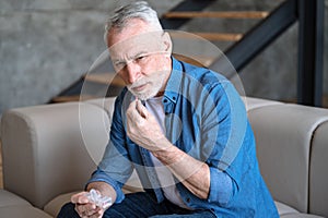 Senior man taking antibiotics, antidepressants, painkiller tablets to relieve pain