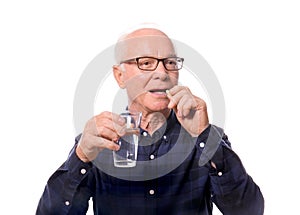 Senior man taking medicine against white background