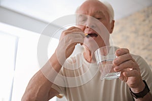 Senior man taking medicine at home