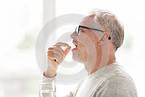 Senior man taking medicine pill at home