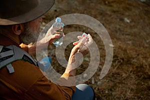 Senior man taking medicine pills during hiking on forest closeup