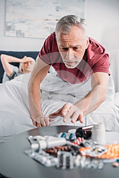 Senior man taking medicines from table in bedroom
