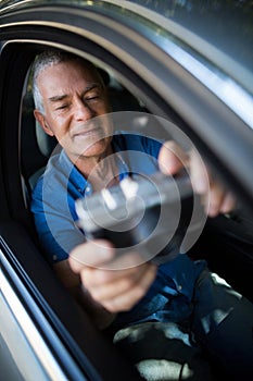 Senior man taking selfie with camera while sitting in car