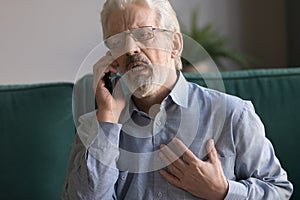 Senior man talking on phone calling 911 having heart attack