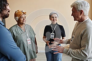 Senior man talking to group of people in support group