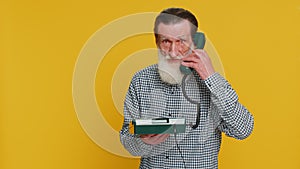 Senior man talking on wired landline vintage telephone, advertising proposition of conversation