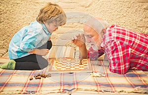 Senior man teaching his grandson to play chess. Handsome grandpa and grandson are playing chess while spending time