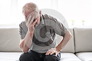 Senior man thinking and sitting on sofa at home like sad