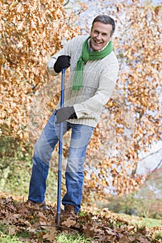 Senior man tidying autumn leaves