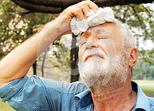 Senior man tired Wiping sweat with a towel in the park, health care concept