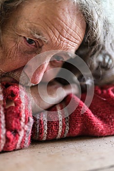 Senior man in torn sweater with worry in his eyes
