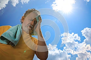 Senior man with towel suffering from heat stroke outdoors, low angle view. Space for text