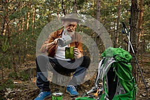 Senior man traveler using portable gas burner to cook dinner