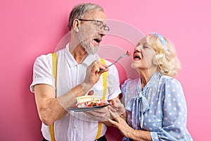 senior man treats a woman with a cake, elderly couple celebrating