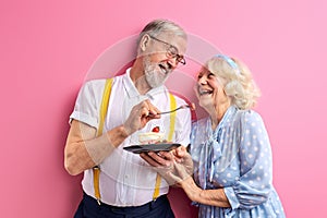 senior man treats a woman with a cake, elderly couple celebrating