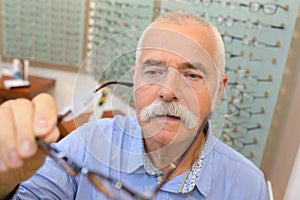 Senior man trying new eyeglasses on optical store