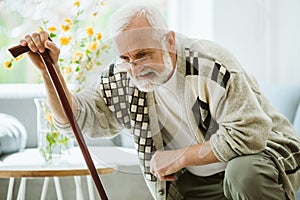 Senior man trying to stand up with cane