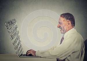 Senior man typing on his laptop computer with screen made of alphabet letters