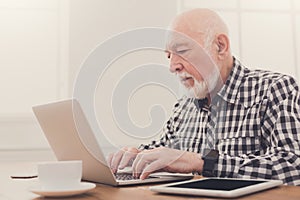 Senior man typing on laptop copy space photo