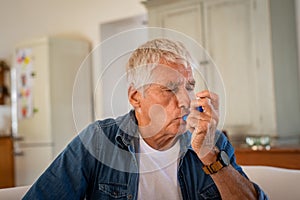 Senior man using asthma pump photo