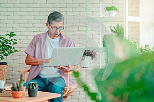 Senior man using computer laptop in indoor home garden