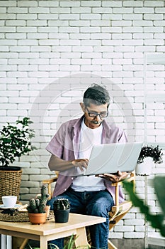 Senior man using computer laptop in indoor home garden