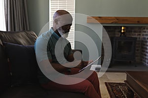 Senior man using digital tablet in living room