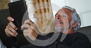 Senior man using digital tablet on sofa 4k
