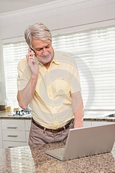 Senior man using his laptop on the phone