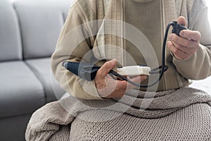 Senior man using a home blood pressure machine to check his vital statistics sitting at the living room