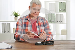 Senior man using lancet pen at table. Diabete photo