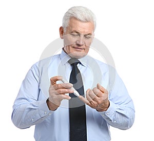 Senior man using lancet pen on white. Diabetes control photo