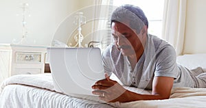 Senior man using laptop in bedroom 4k