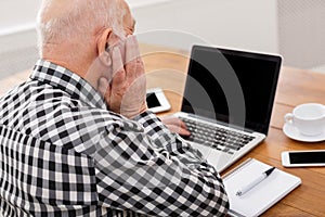 Senior man using laptop with blank screen mockup