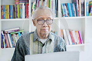Senior man using a laptop computer in library