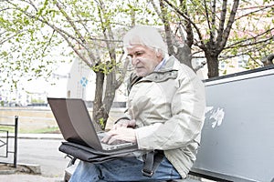 Senior man using laptop computer outdoors